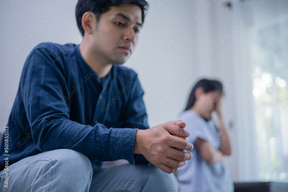 Young couple lost in sad thoughts sitting together on couch thinking feels troubled about problems in relationships, unwanted unexpected pregnancy and difficult decision, break up and divorce concept.