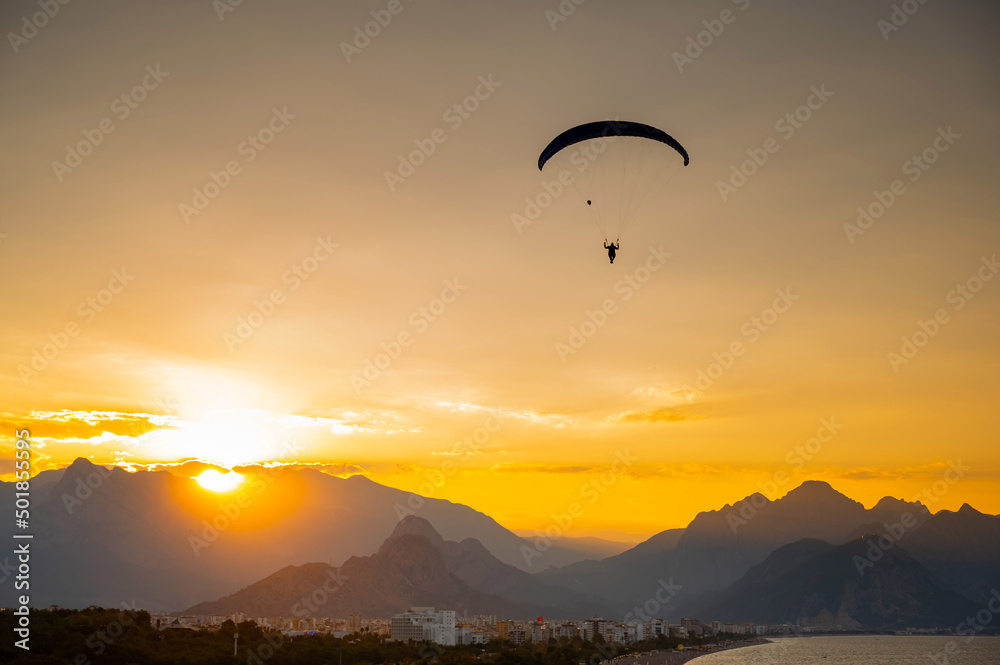 Silhouette of a man on a paraglider flying over the sea at sunset. Silhouette of a man on a paraglider flying over the sea at sunset.