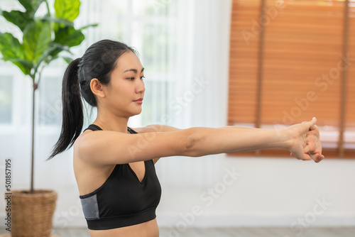 Calm of Asian woman in sportwear stretching muslce to warm up breathing and meditation with yoga at home.Healthy female stretching muscle comfortable and relax before exercise ready to workout © 220 Selfmade studio