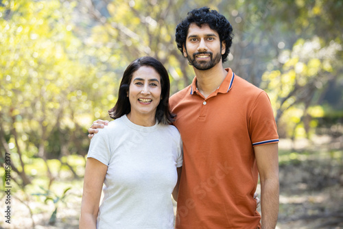 Portrait of happy indian couple standing outdoors in the park, Smiling urban city man and woman wearing casual t-shirt, looking at camera. husband wife.