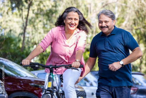 Happy Senior indian couple riding bicycle, summer activity, Mature adult people enjoy adventures fun sports Healthy and fit old, Aging. 