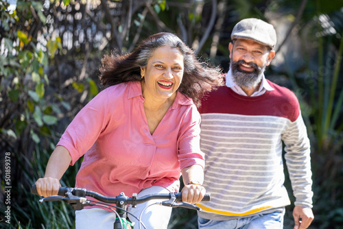 Aging, Happy Indian Senior couple riding bicycle outdoors, active mature adults lifestyle., Elderly people Fitness healthcare, Retirement life. Carefree, mental health, stress free 