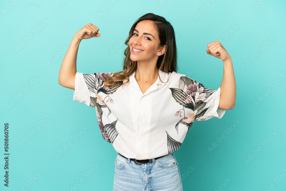 Obraz premium Young woman over isolated blue background doing strong gesture