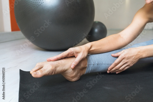 Fotografia A woman performs a stretching of the muscles of the foot, sits on a mat in the r