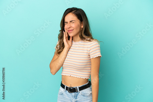 Young woman over isolated blue background with toothache