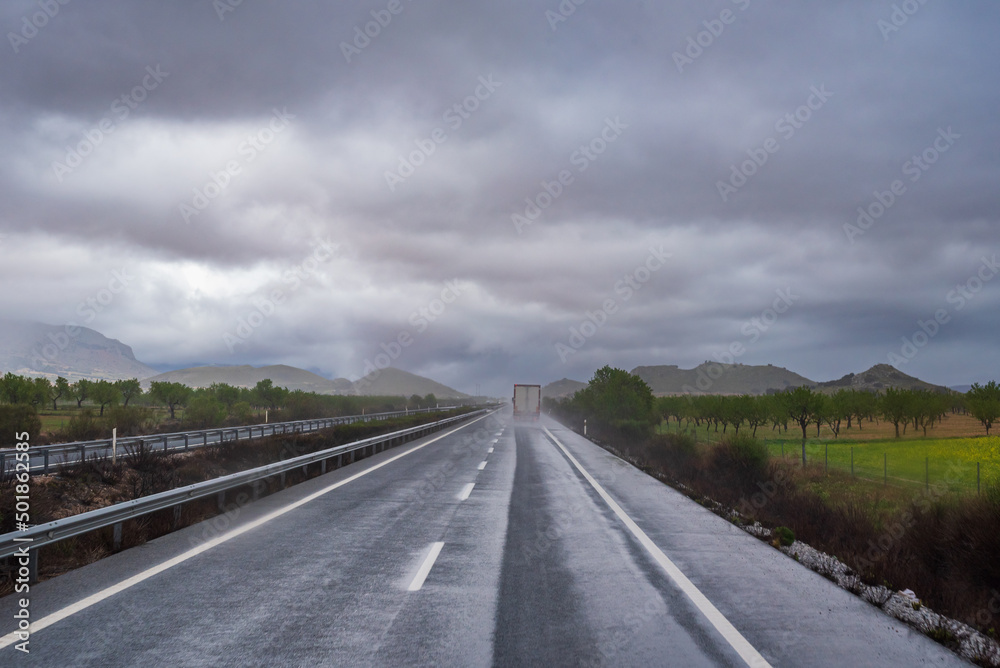 Fototapeta premium Truck circulating on a rainy day, raising a cloud of water as it passed.