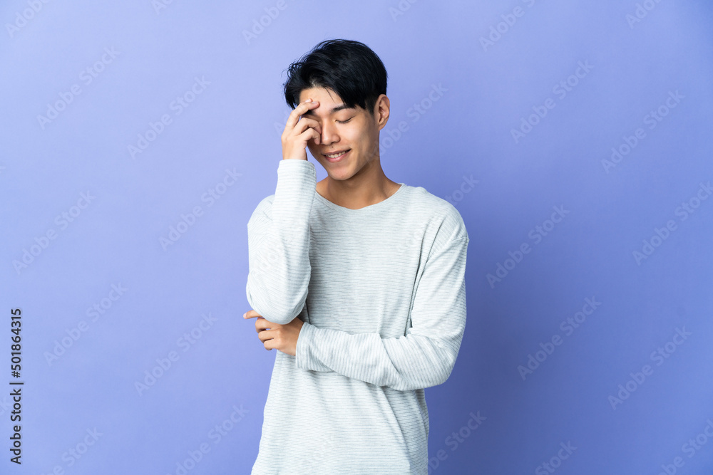 Young Chinese man isolated on purple background laughing