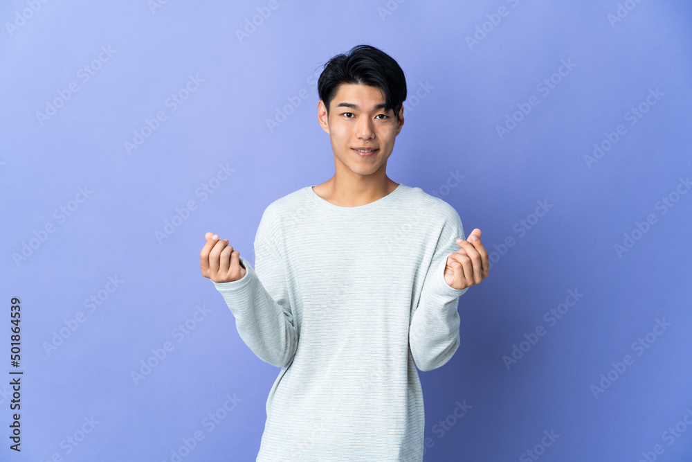 Young Chinese man isolated on purple background making money gesture Young Chinese man isolated on purple background making money gesture