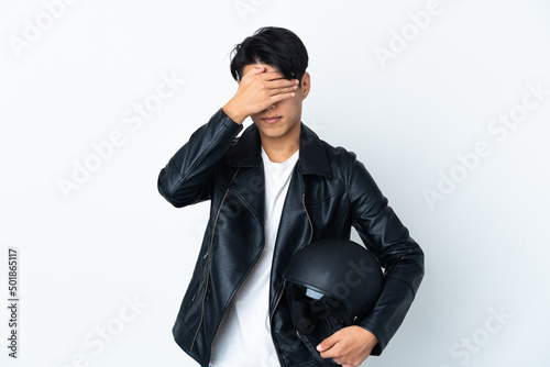 Chinese man with a motorcycle helmet isolated on white background covering eyes by hands. Do not want to see something