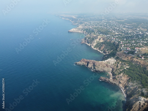 Aerial view from above on calm azure sea and volcanic rocky shores. Small waves on water surface in motion blur. Nature summer ocean sea beach background. Nobody. Holiday, vacation and travel concept