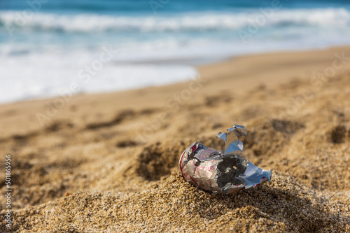 Pollution of the planet with human waste. An empty tin can thrown away by the sea on the beach. Garbage pollution problem of nature