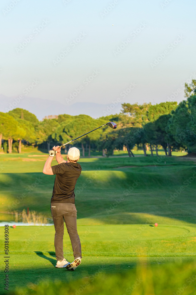 Golfer spielt einen Ball auf einem Golfplatz in der Abendsonne Golfer spielt einen Ball auf einem Golfplatz in der Abendsonne