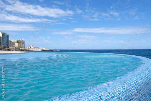 Blue clear water surface in swimming pool in a resort with sea views. Summer Vacation and rest concept. Luxury beach villa house. Blue tile mosaic pattern.