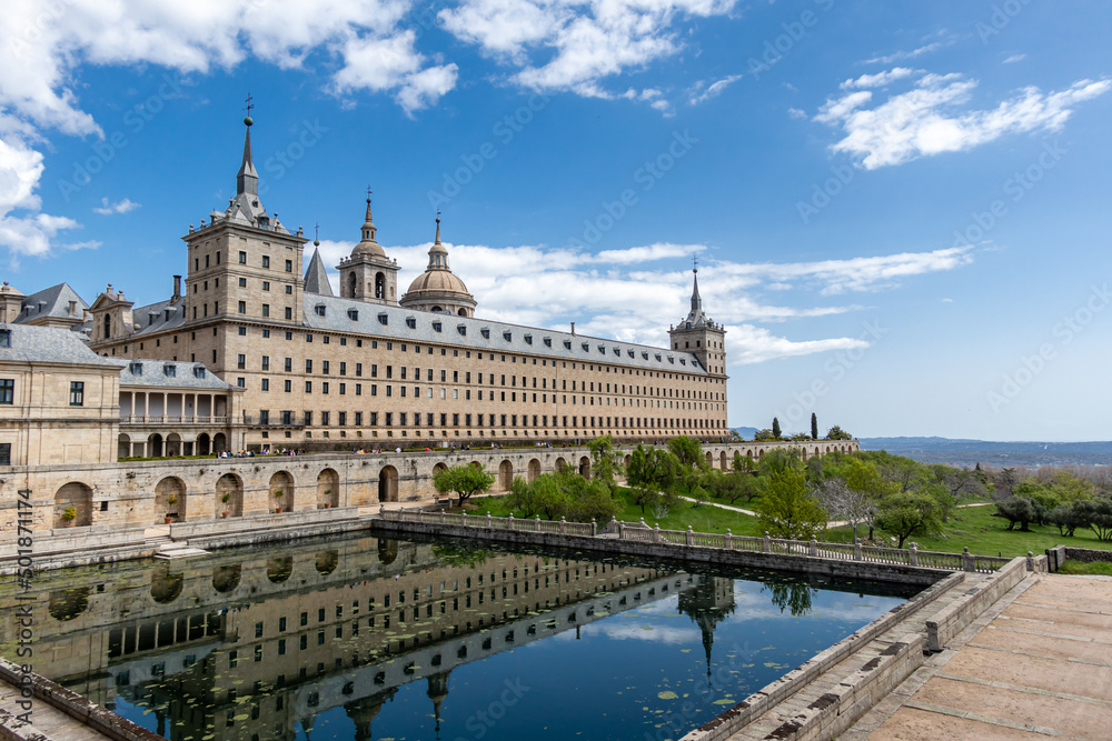 monastery of San Lorenzo de El Escorial with tourists strolling through its gardens and patios in Madrid