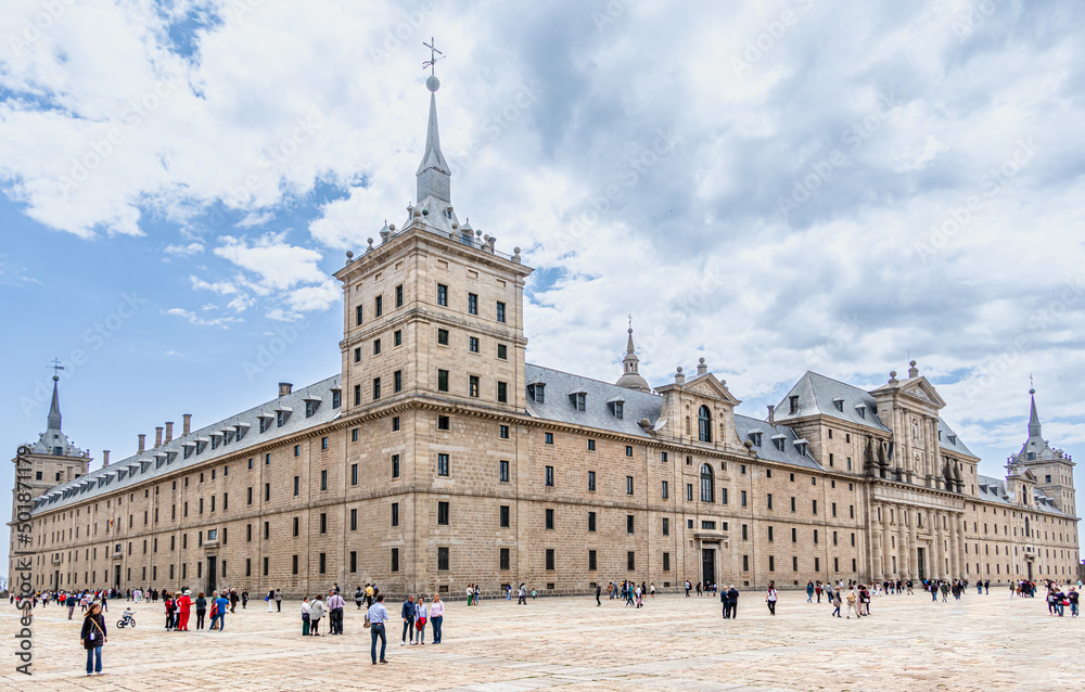monastery of San Lorenzo de El Escorial with tourists strolling through its gardens and patios in Madrid