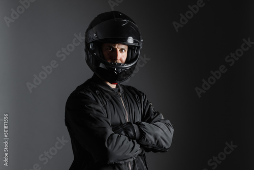 Studio shot of Motorcyclist biker in black equipment with crossed arms.