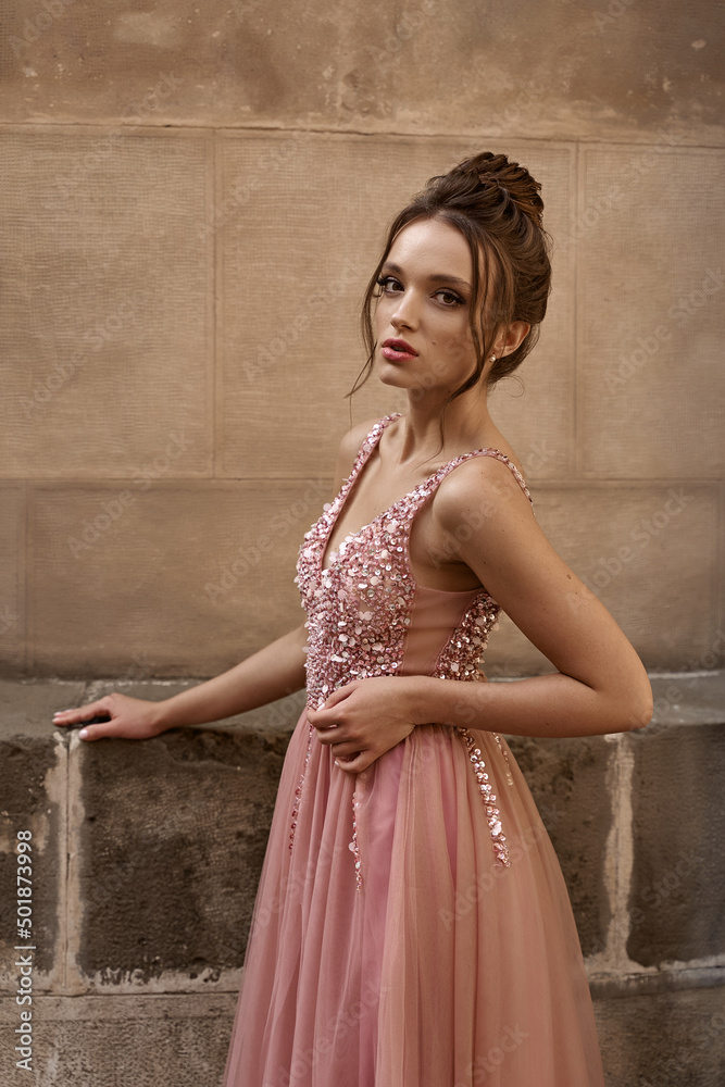 Portrait of beauiful European girl bridesmaid in classic pink dress