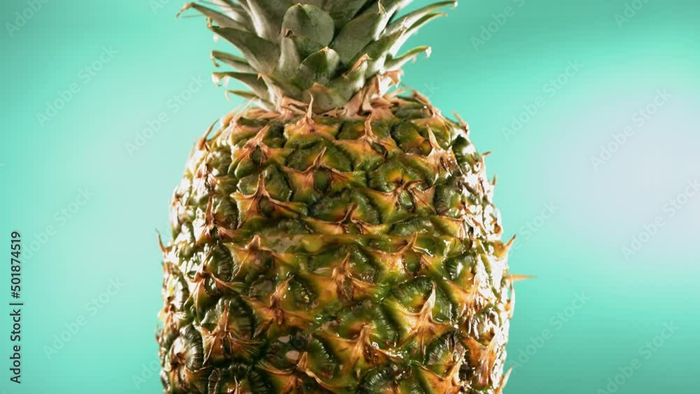 Half Pineapple falling and splashing on turquoise background. Food levitation concept. Slow Motion