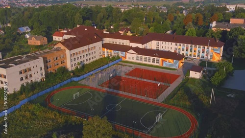 Exterior of school building with playground. Ground in the park. School and playground landscape. Basketball court new fenced in park. Trees urban place for children. photo