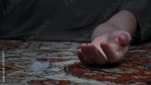 Addict's hand with syringe falls to floor just pricked heroin drugs. Slow Motion. Overdose, meth syringe falls out of weakened hand of die junkie. Social degradation, self-destruction, narcomaniac. 4K photo