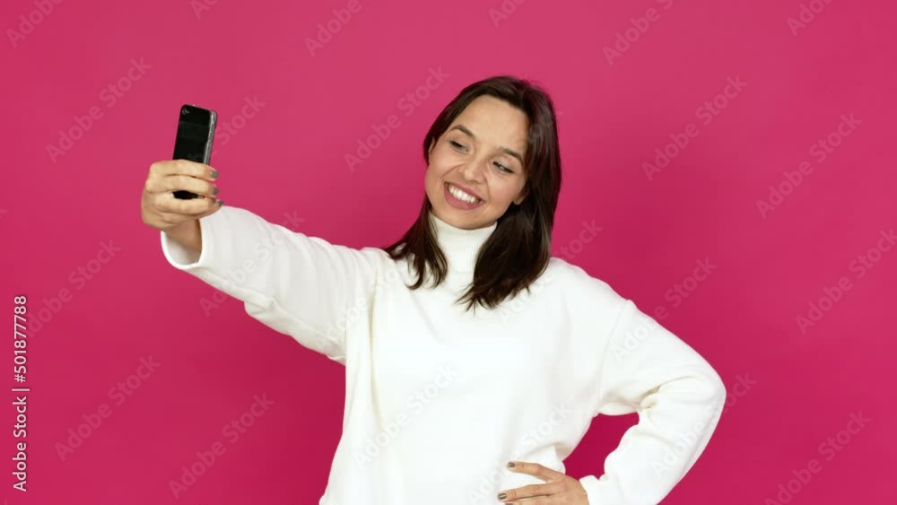 Young brunette woman using mobile phone and doing a selfie over isolated background Young brunette woman using mobile phone and doing a selfie over isolated background