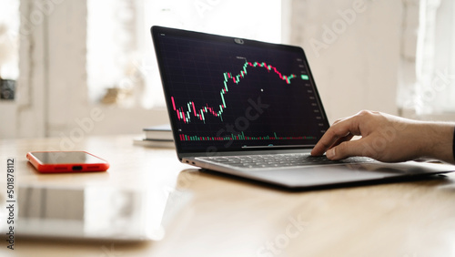 Exchange finance stocks charts monitor trader, candles online, workplace man uses laptop report in company in office.