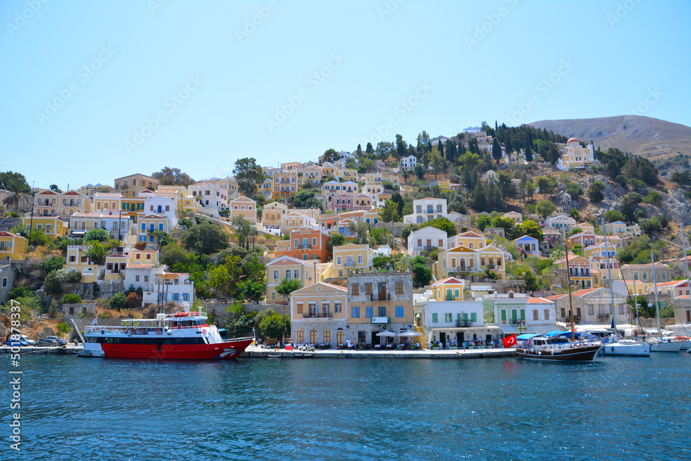 greek island with waterfront and traditional coloured houses and boats