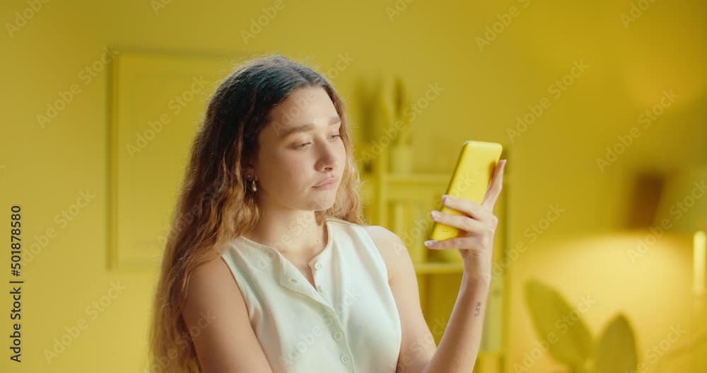 Close up portrait of a beautiful young woman with long hair using cellphone and reading message seriously, browsing products online or shopping online. Female model using mobile phone in studio Close up portrait of a beautiful young woman with long hair using cellphone and reading message seriously, browsing products online or shopping online. Female model using mobile phone in studio