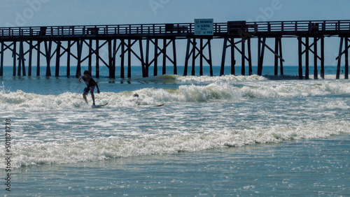 Two kids surfing at Flagler Beach Pier in Florida.