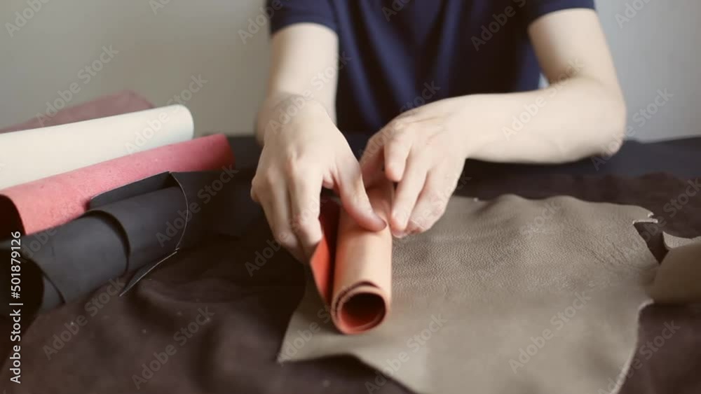 A professional craftsman, sitting at his desk and choosing cowhide in a roll for making leather products A professional craftsman, sitting at his desk and choosing cowhide in a roll for making leather products