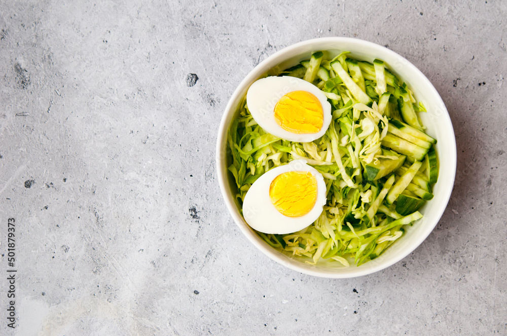 diet cabbage salad with cucumber and boiled egg on a gray table, top view, a place to copy diet cabbage salad with cucumber and boiled egg on a gray table, top view, a place to copy