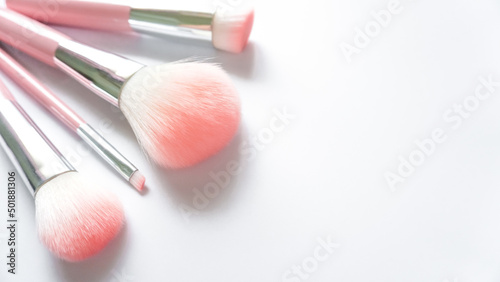 Top view of several pink makeup brushes on a white background