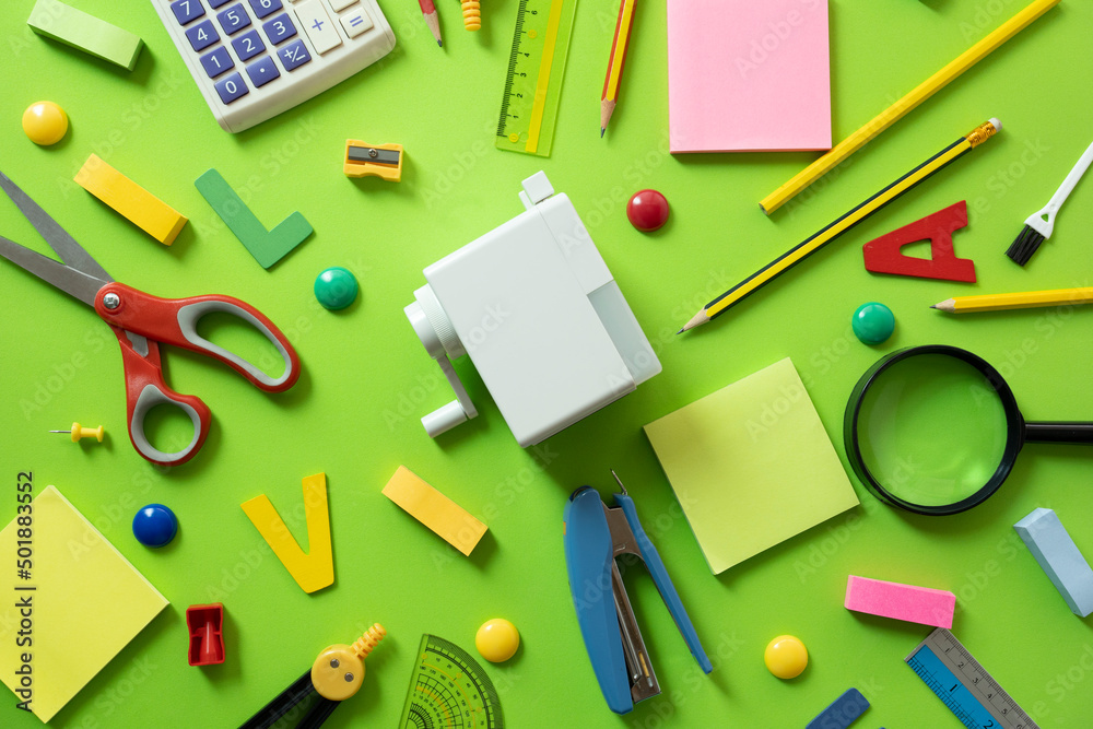 Different stationery and calendar on green table background, flat lay. Space for text, back to school concept