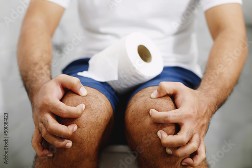 Cuadro en lienzo Man suffers from diarrhea hand hold tissue paper roll in front of toilet bowl