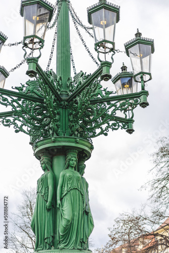 Photography street gas lantern with figures at its base, Hradcany, Prague, Czech Republik