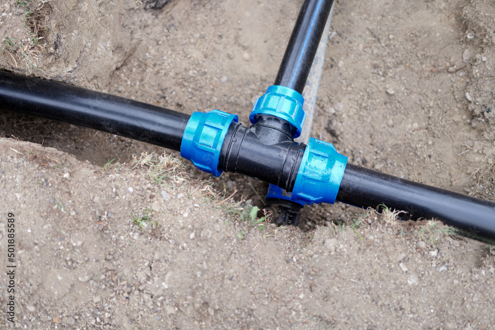 Installed PVC water pipes are assembled and laid in trench at construction site