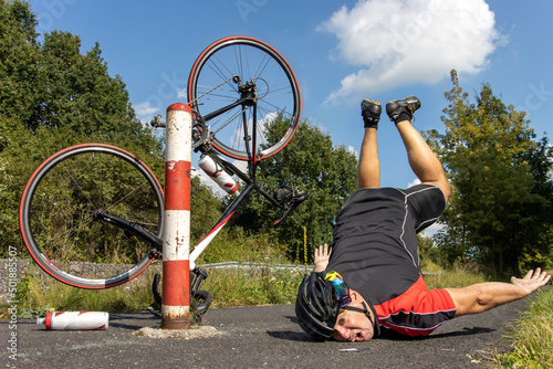The unhappy cyclist falls of the bike beside the barrier on a bicycle path. photo