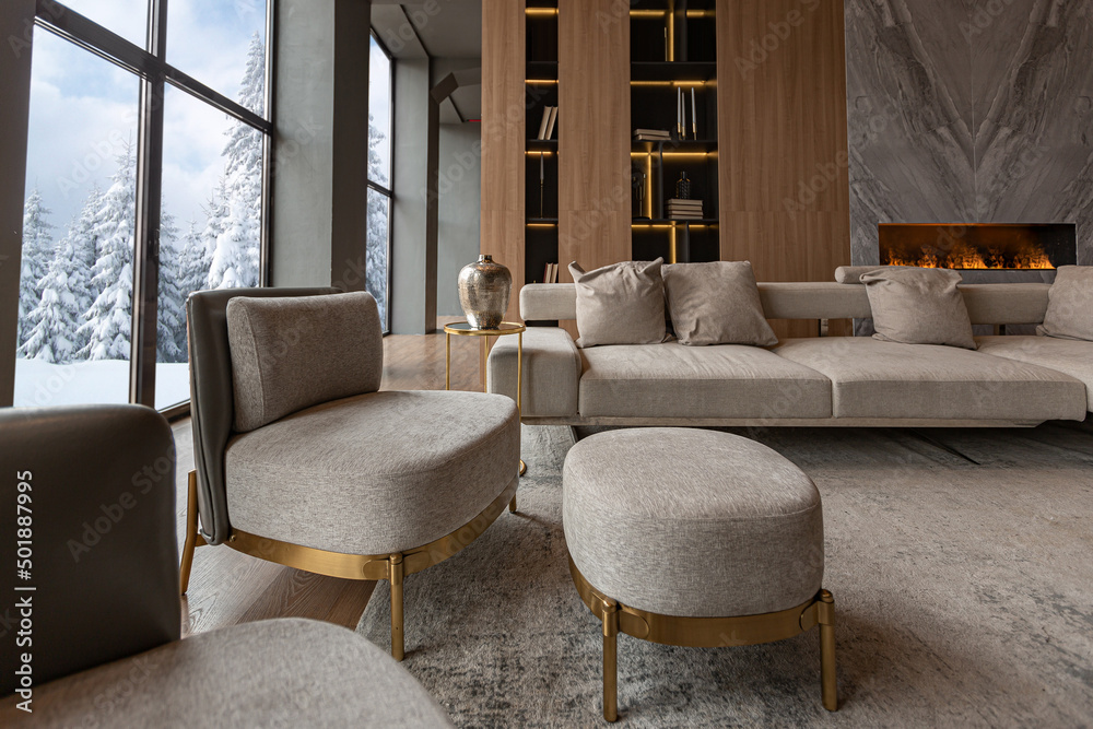 living room, marble wall fireplace and stylish bookcase in chic expensive interior of luxury country house with a modern design with wood and led light, gray furniture with gold elements