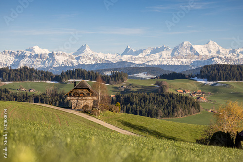 traditional wooden farm house in Emmental in spring in front of the Bernese Alps photo