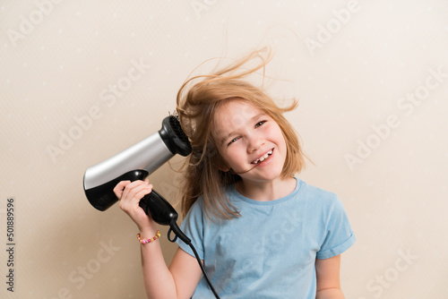 little girl dries her hair with a hair dryer with a comb attachment. hair care at home. simple hairstyles. shampoo and thermal protection for hair.