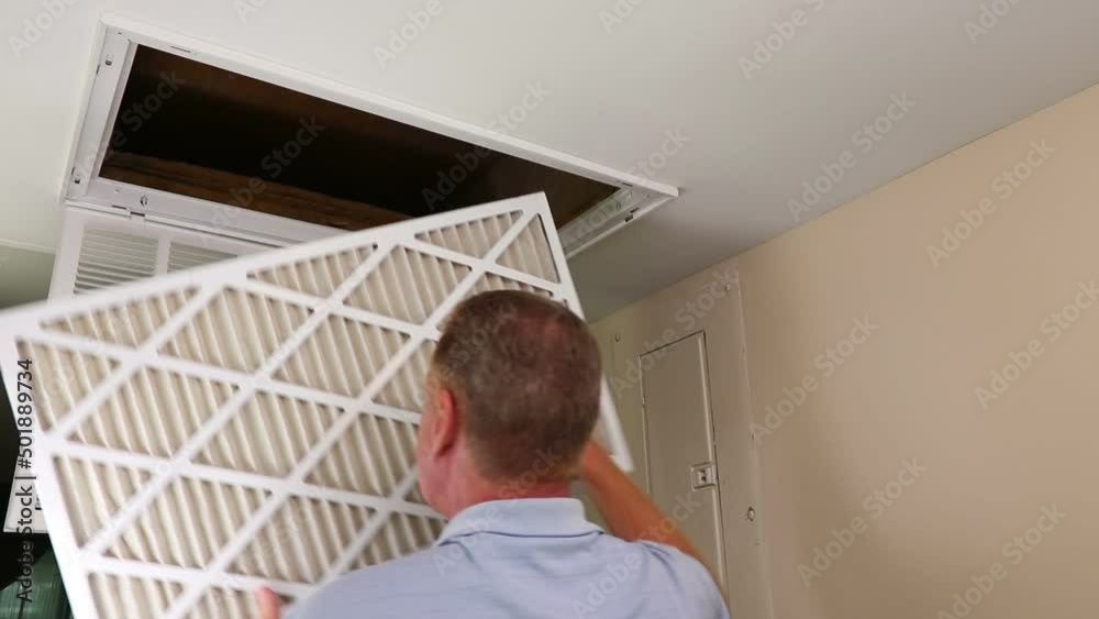 Air filter being replaced from a clean to dirty one in monthly maintenance as a home furnace by a home owner. Maintenance replacement of an air filter in a ceiling of a condo by a mature adult male.