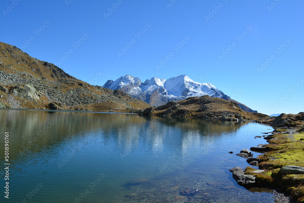 A mountain lake, lai blau, in the swiss alps with a snowy mountain, the piz scopi in the background