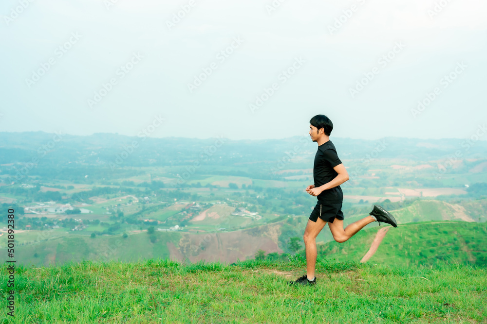 Obraz premium Portrait of an Asian male trail runner running. On the high mountains there are beautiful views. It's a trail running practice. on a bright day Behind is a beautiful mountain view.