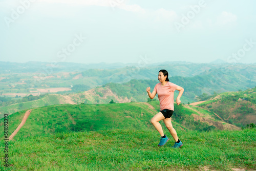 Asian women trail runners training on a high mountain. The back view is high mountain, beautiful scenery. In the evening the air is fresh and atmosphere is good.