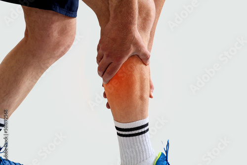 Man in sport clothes holding leg muscle pain and numbness from muscle cramps isolated on white background. Calf muscle pain in runner.  photo