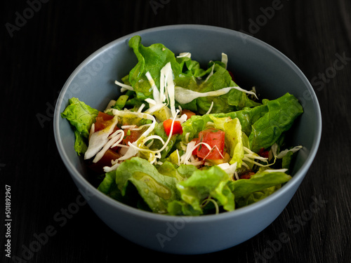 Light salad in a bowl on a dark background.