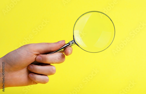 Woman hand with magnifying glass on yellow background. Analytic and statistic data study, research conducting, information check, scrutiny and audit concept. High quality photo