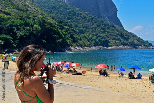 Young brazilian woman photographing in the beach, Rio