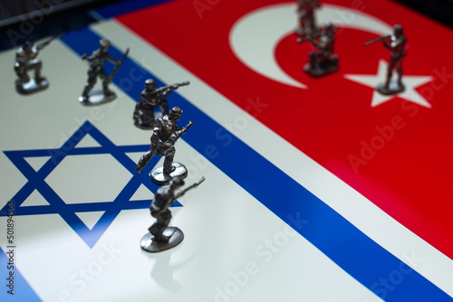 The concept of the economic and political crisis between Israel and Turkey, toy soldiers attacking each other against the background of national flags.
