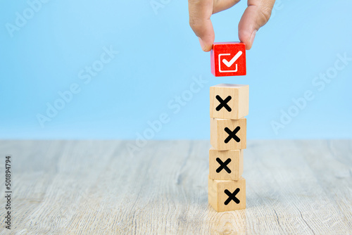 Hand choose check mark on cube wooden toy block stack with cross symbol for true or false changing mindset or way of adapting to change leader and transform quiz answer and poll concept.